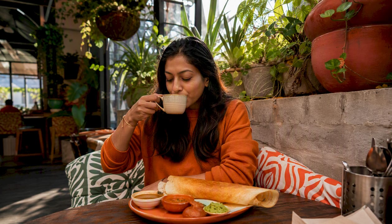 Woman enjoying South Indian breakfast and chai in Melbourne cafe