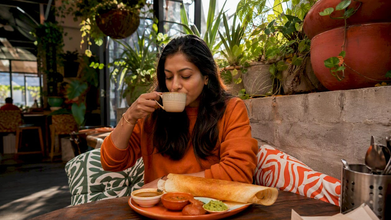 Woman enjoying South Indian breakfast and chai in Melbourne cafe
